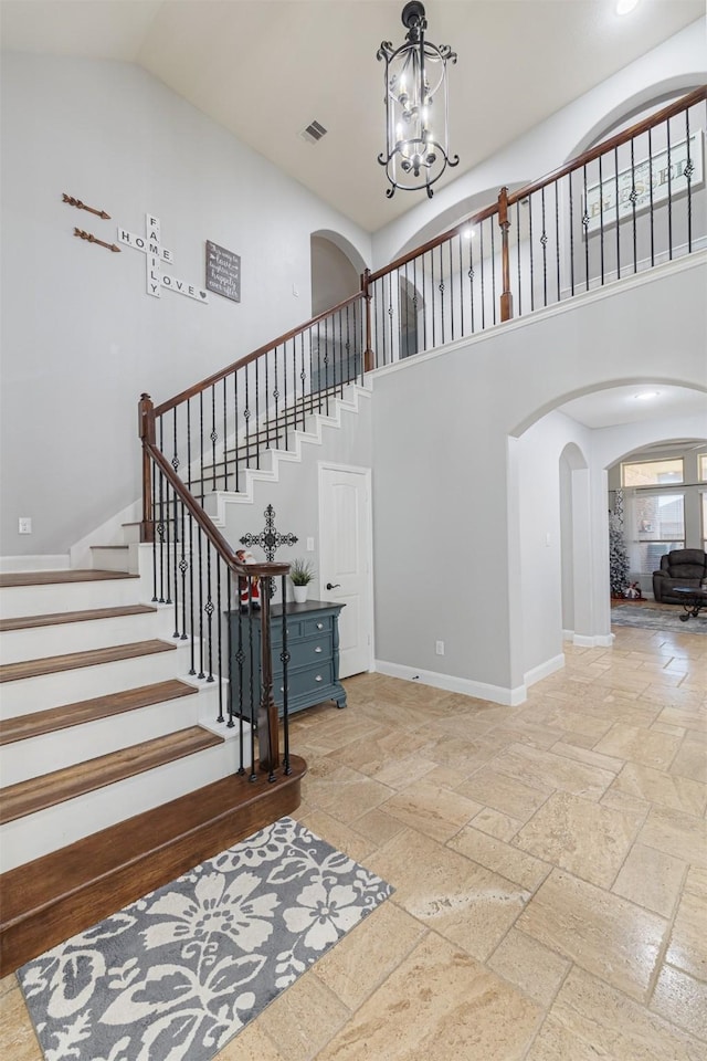 stairs with a towering ceiling and an inviting chandelier