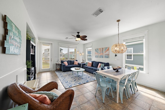 tiled dining area featuring ceiling fan with notable chandelier