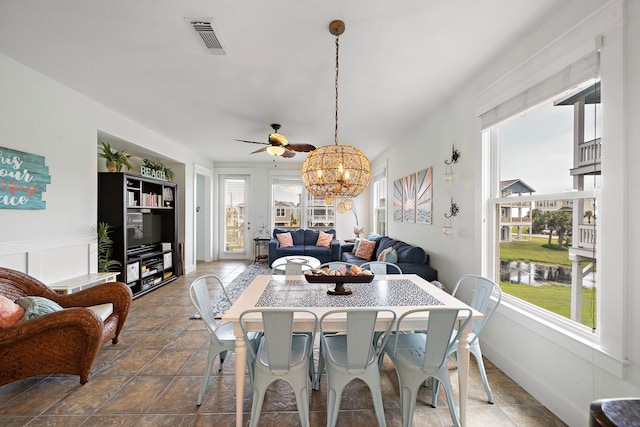 dining room with built in shelves, ceiling fan with notable chandelier, and plenty of natural light