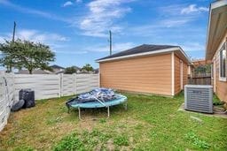 view of yard featuring a trampoline and central AC unit