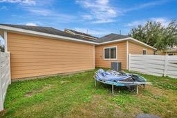 exterior space featuring central air condition unit, a lawn, and a trampoline