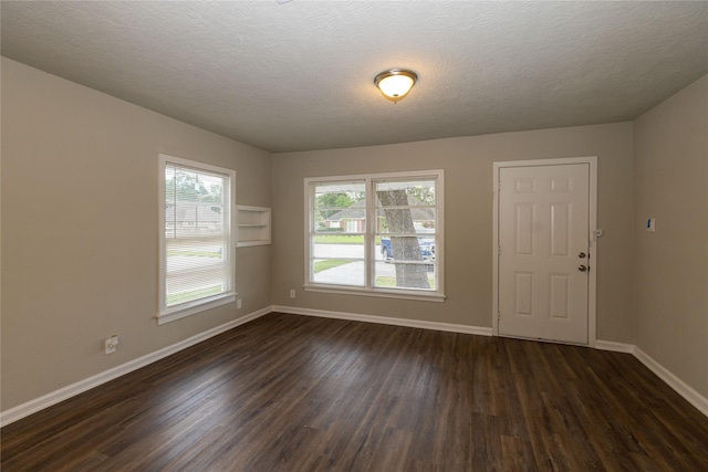 spare room with a textured ceiling and dark hardwood / wood-style flooring