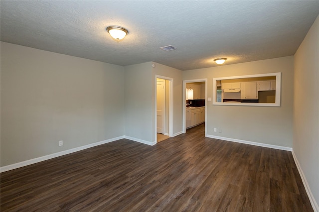 empty room featuring dark wood-type flooring and a textured ceiling