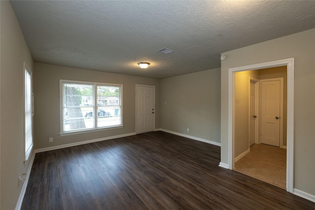 empty room with dark wood-type flooring and a textured ceiling