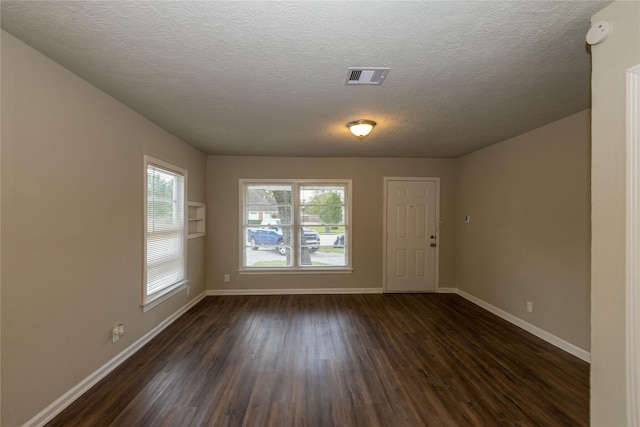 unfurnished room with a textured ceiling and dark hardwood / wood-style flooring