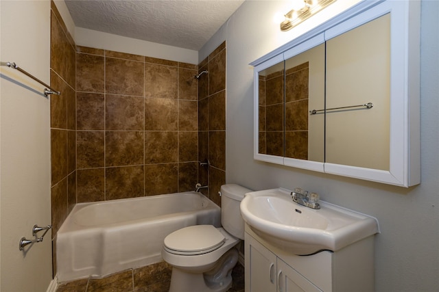 full bathroom featuring toilet, a textured ceiling, tiled shower / bath, and vanity