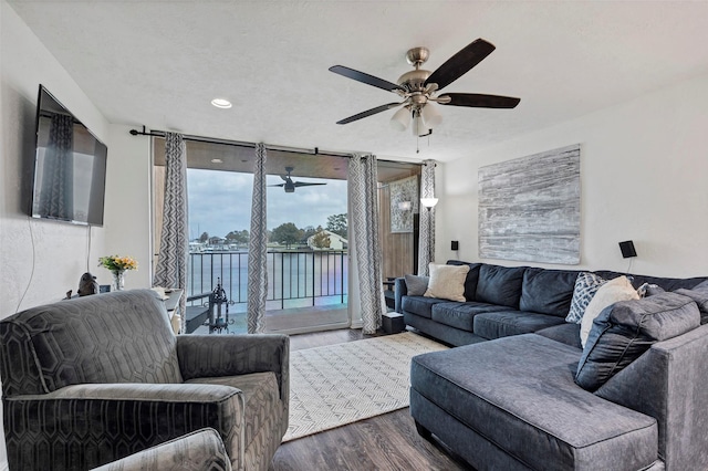 living room featuring ceiling fan, wood-type flooring, expansive windows, and a water view