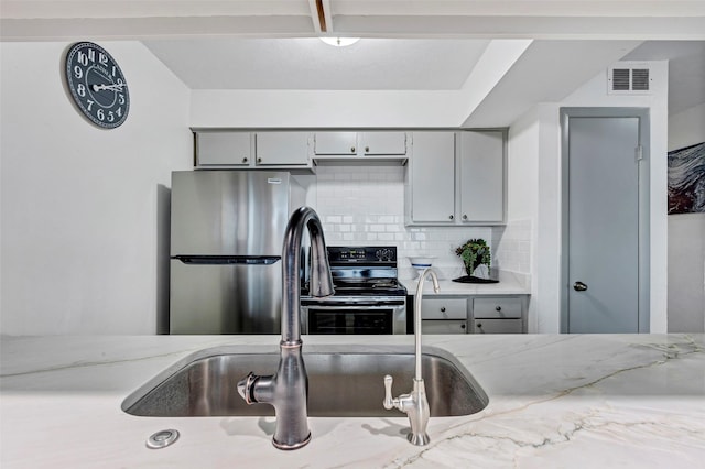 kitchen with sink, gray cabinetry, appliances with stainless steel finishes, and decorative backsplash