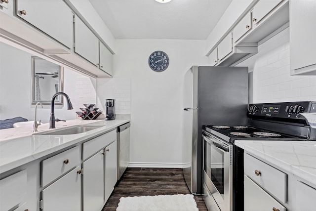 kitchen with appliances with stainless steel finishes, sink, backsplash, white cabinetry, and dark hardwood / wood-style floors