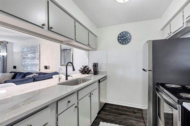 kitchen featuring appliances with stainless steel finishes, sink, light stone countertops, dark hardwood / wood-style floors, and decorative backsplash