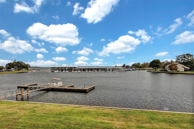 view of dock with a lawn and a water view