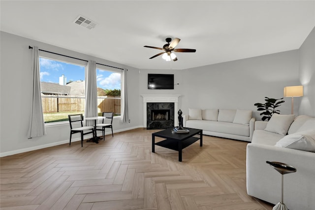 living room with ceiling fan, a high end fireplace, and light parquet floors