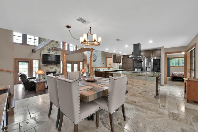 dining space with sink, a wealth of natural light, a notable chandelier, and a fireplace