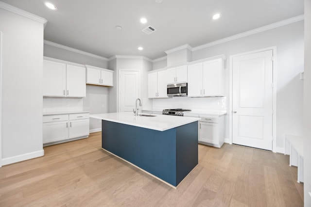 kitchen with sink, a center island with sink, white cabinets, and stove