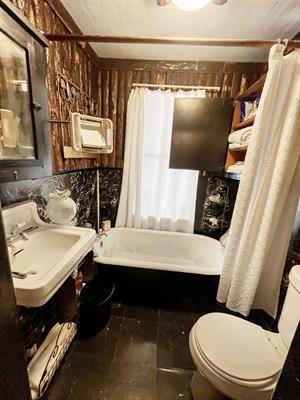 full bathroom featuring sink, toilet, shower / bath combination with curtain, and an AC wall unit