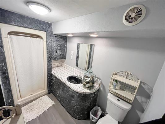 bathroom featuring wood-type flooring, toilet, and walk in shower