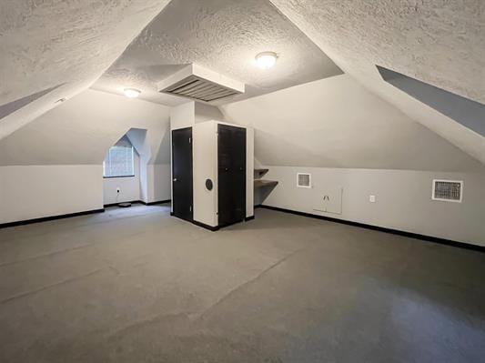 additional living space with a textured ceiling and vaulted ceiling