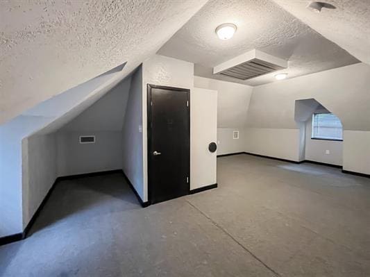 bonus room with a textured ceiling and lofted ceiling