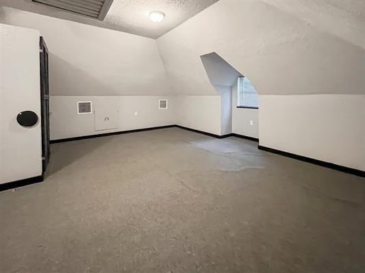 bonus room featuring a textured ceiling and lofted ceiling