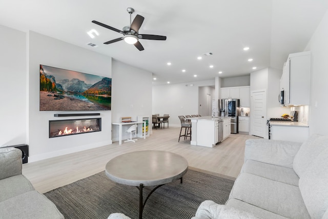 living room with ceiling fan and light wood-type flooring