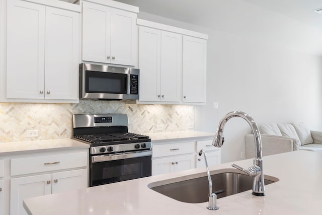 kitchen with stainless steel appliances, sink, white cabinets, and decorative backsplash