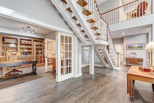 interior space with french doors, a towering ceiling, and wood-type flooring