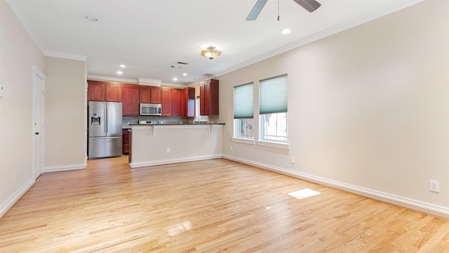 kitchen with a kitchen bar, tasteful backsplash, light hardwood / wood-style flooring, ornamental molding, and appliances with stainless steel finishes