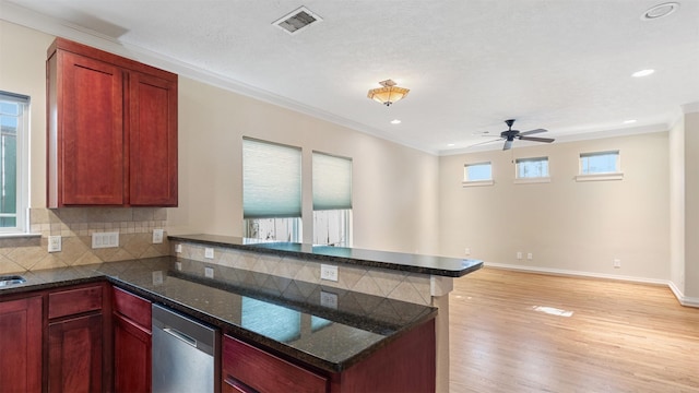 kitchen featuring tasteful backsplash, light hardwood / wood-style flooring, dark stone countertops, ornamental molding, and dishwasher