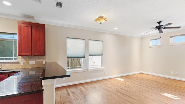 kitchen featuring crown molding, decorative backsplash, ceiling fan, and light wood-type flooring