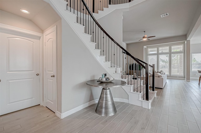 entrance foyer featuring ceiling fan, light hardwood / wood-style floors, and a towering ceiling