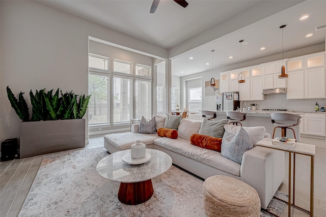 living room featuring ceiling fan, sink, and light hardwood / wood-style floors