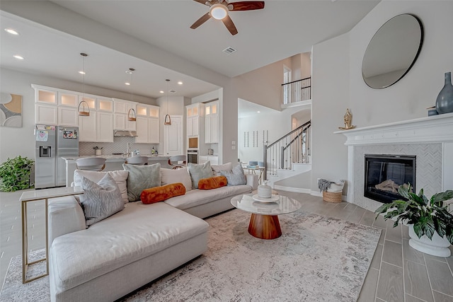 living room featuring a tiled fireplace and ceiling fan