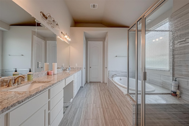 bathroom with independent shower and bath, vanity, and vaulted ceiling