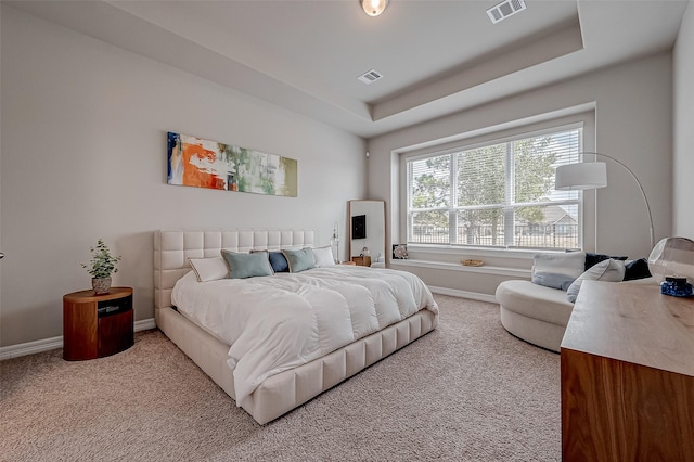 bedroom featuring light carpet and a tray ceiling