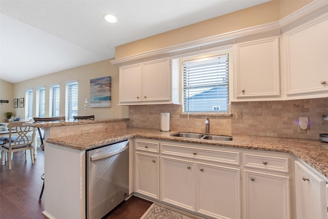 kitchen with light stone countertops, white cabinetry, sink, kitchen peninsula, and stainless steel dishwasher