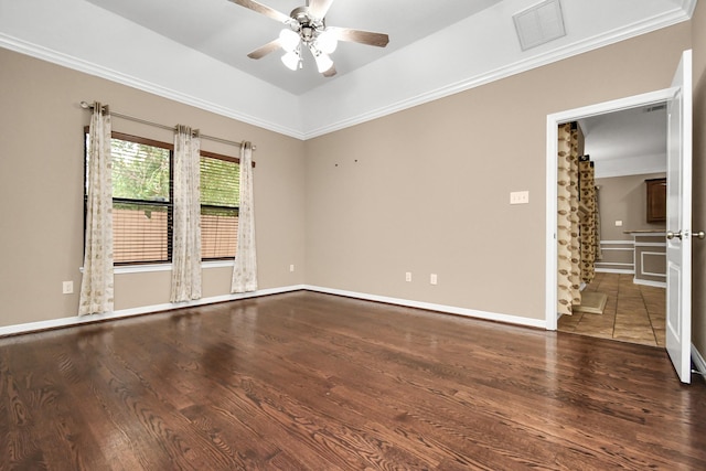 empty room with ceiling fan, dark hardwood / wood-style flooring, ornamental molding, and vaulted ceiling