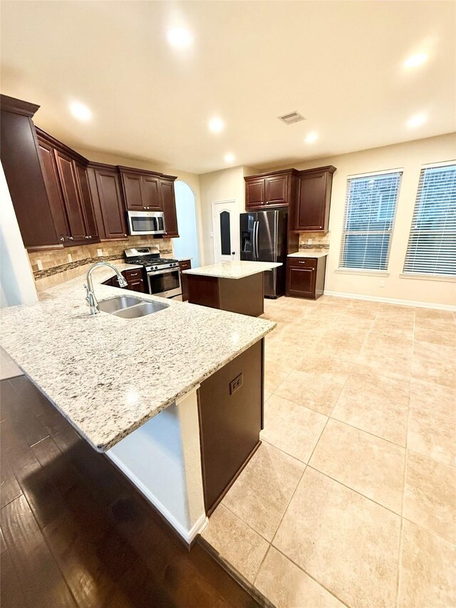 kitchen featuring a kitchen island, tasteful backsplash, sink, kitchen peninsula, and stainless steel appliances