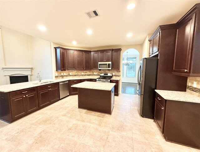 kitchen with sink, appliances with stainless steel finishes, a center island, decorative backsplash, and kitchen peninsula