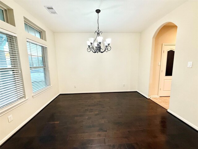 unfurnished dining area featuring an inviting chandelier and dark hardwood / wood-style floors