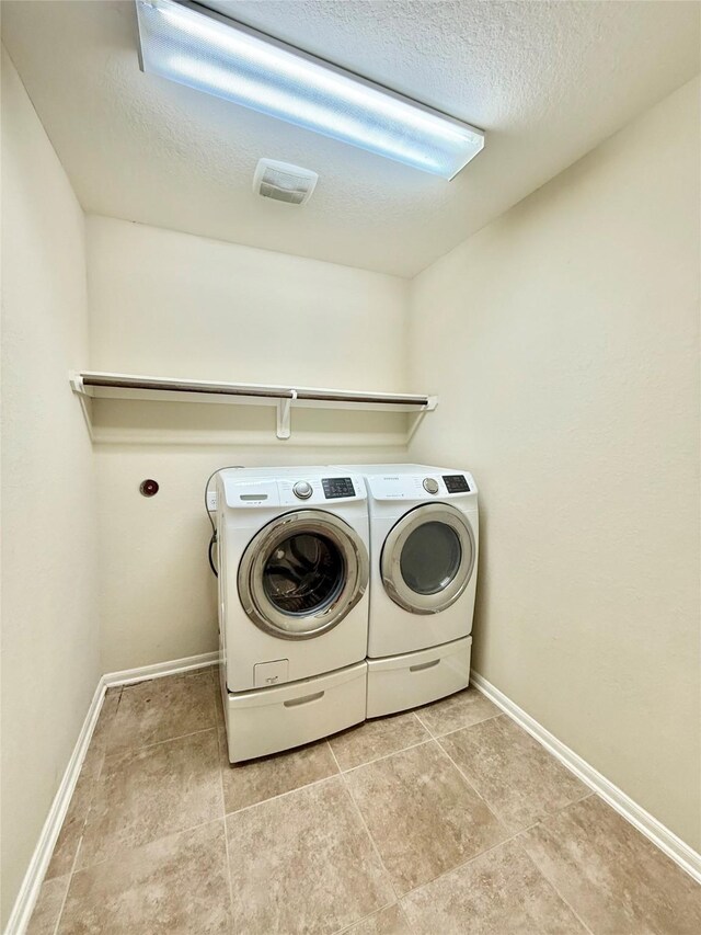 washroom with washing machine and dryer and a textured ceiling