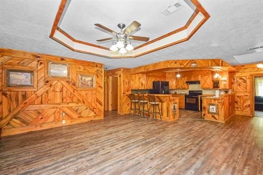 kitchen featuring a center island, range, a raised ceiling, dark hardwood / wood-style flooring, and a breakfast bar area