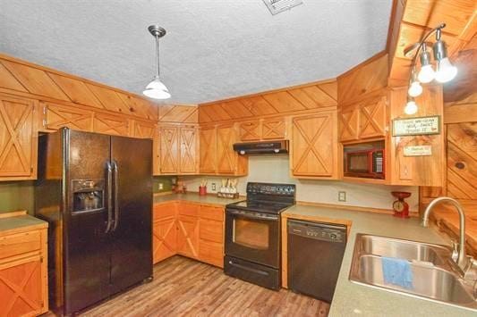 kitchen featuring decorative light fixtures, black appliances, sink, and light hardwood / wood-style floors