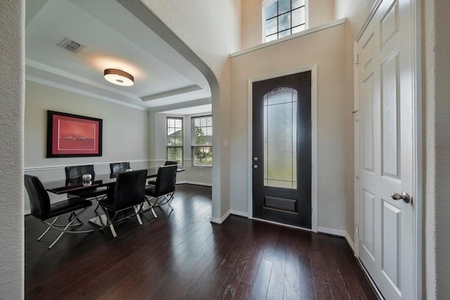 foyer with dark hardwood / wood-style floors, ornamental molding, and a tray ceiling