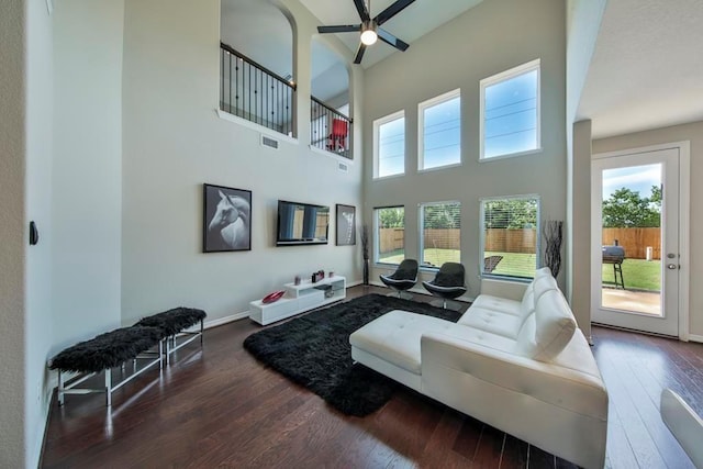 living room with a high ceiling, ceiling fan, and dark hardwood / wood-style flooring