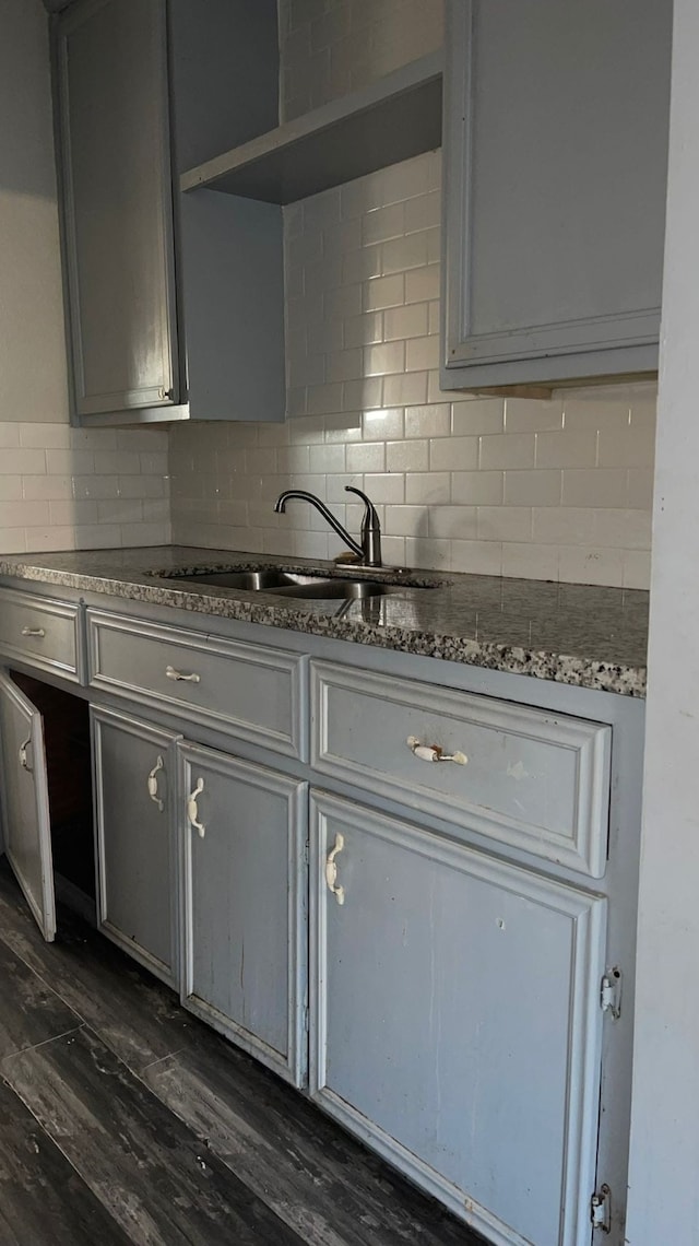 kitchen featuring dark hardwood / wood-style flooring, dark stone counters, tasteful backsplash, sink, and gray cabinets