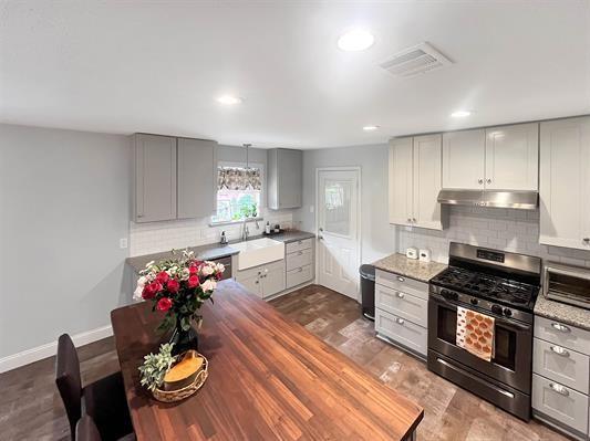 kitchen featuring sink, decorative backsplash, gray cabinets, and stainless steel gas stove