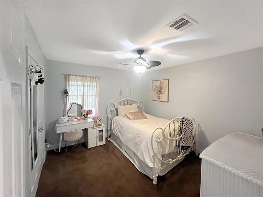 bedroom with ceiling fan and dark carpet