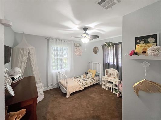 bedroom featuring ceiling fan and dark carpet