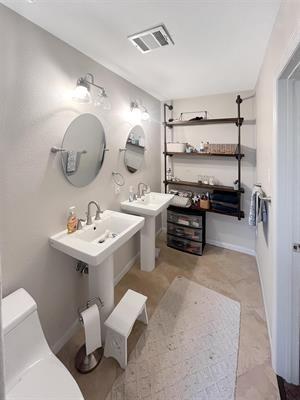 bathroom with toilet and double sink