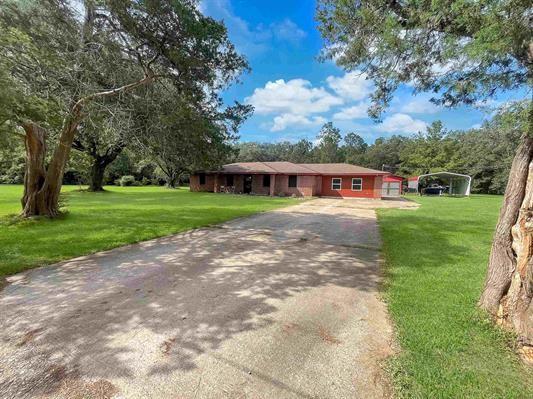 ranch-style home with a garage, a front yard, and a carport